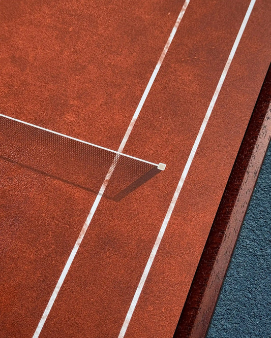 Close-up of French Open Tennis Frame on a tennis court, showing clay court lines and walnut frame edge