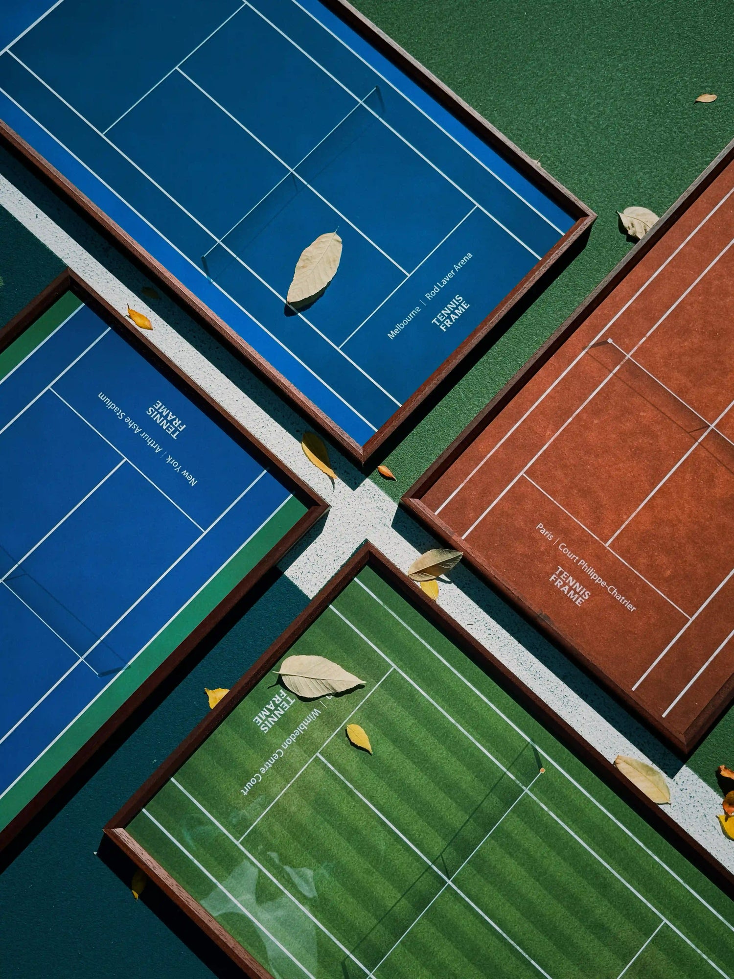 Grand Slam Tennis Frame collection—Wimbledon, US Open, French Open, and Australian Open—angled flat lay on a tennis court with fall leaves