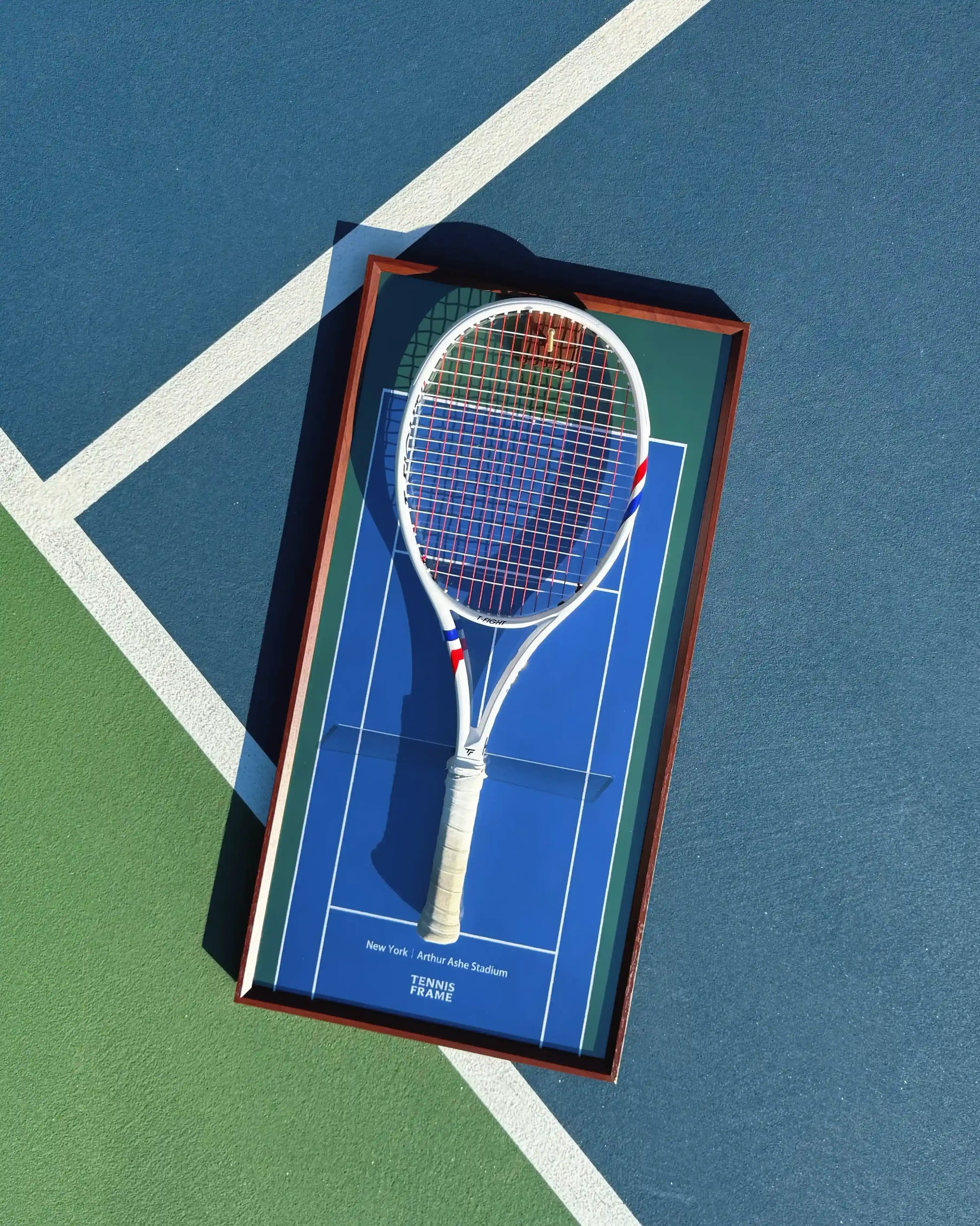 US Open Tennis Frame with white racket, TF 305s, on Arthur Ashe Stadium blue background, angled flat lay on tennis court