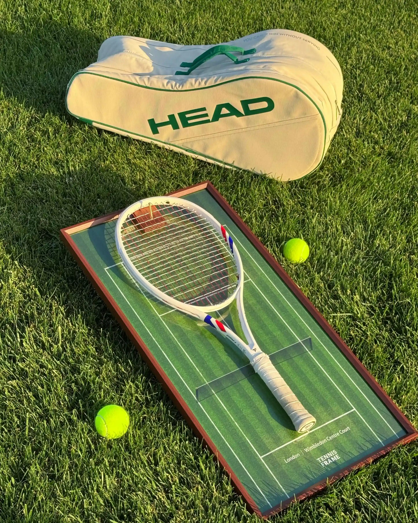 Wimbledon Centre Court Tennis Frame displaying a white racket on grass with Head bag and two tennis balls, golden-hour lifestyle shot