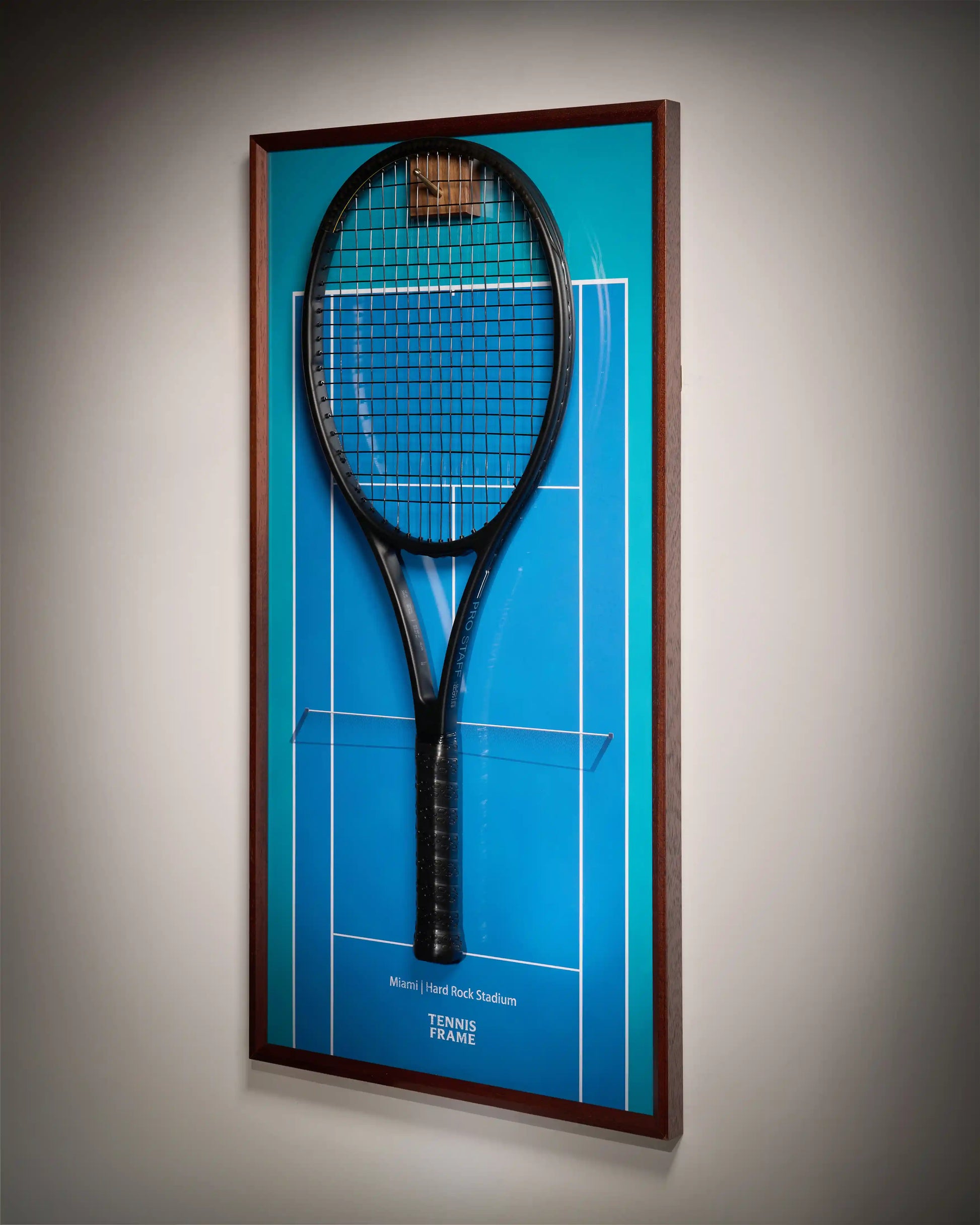 Miami Open tennis racket display frame with blue hard-court background at Hard Rock Stadium, angled side view with walnut frame and hook