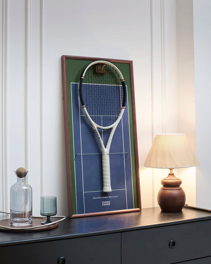 TENNIS FRAME Angled view of the New York Empire Blue Court tennis racket display frame with a mounted racket, featuring a walnut wood frame, brass hook, and premium home decor styling. 