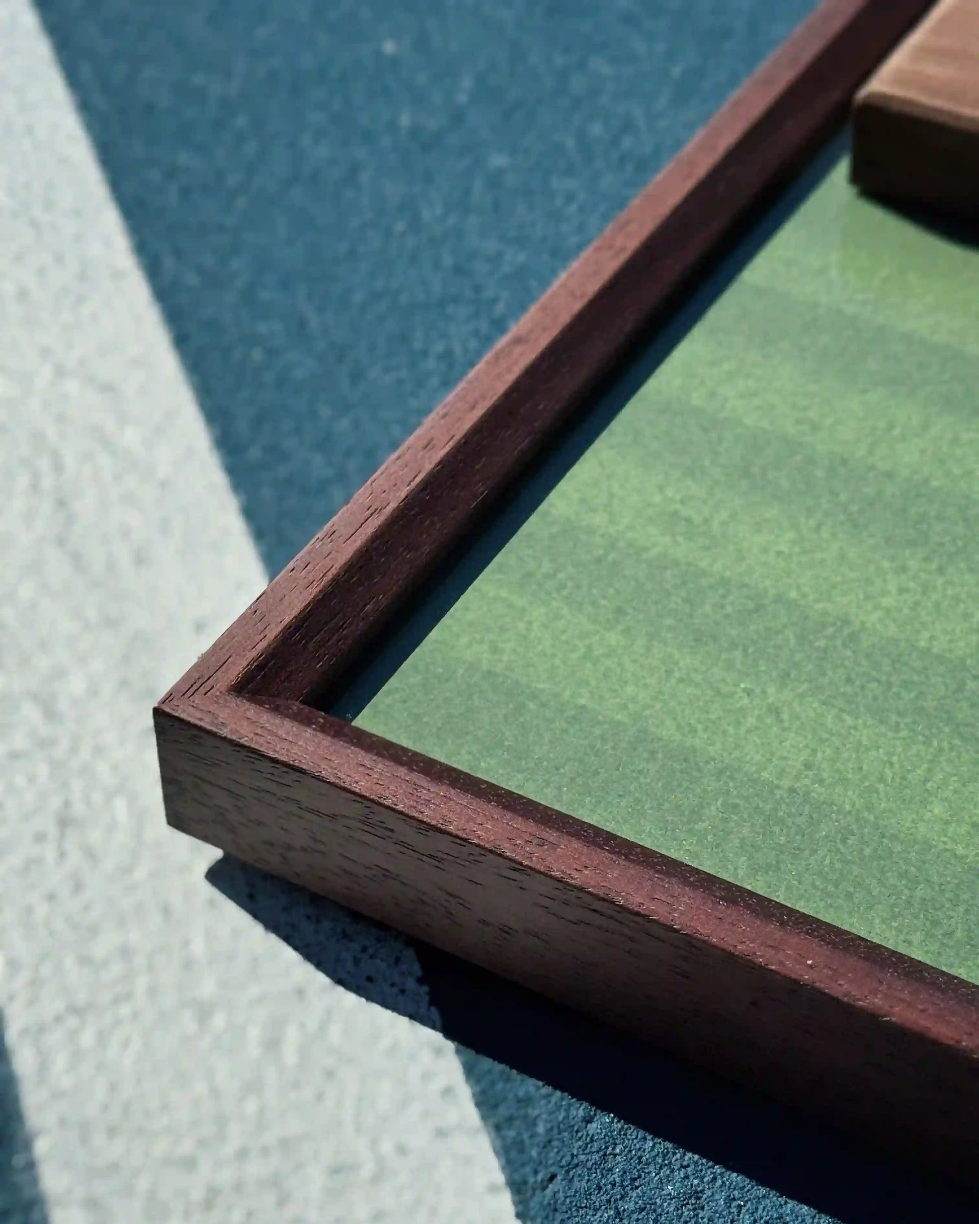 Walnut tennis frame corner detail on green court background