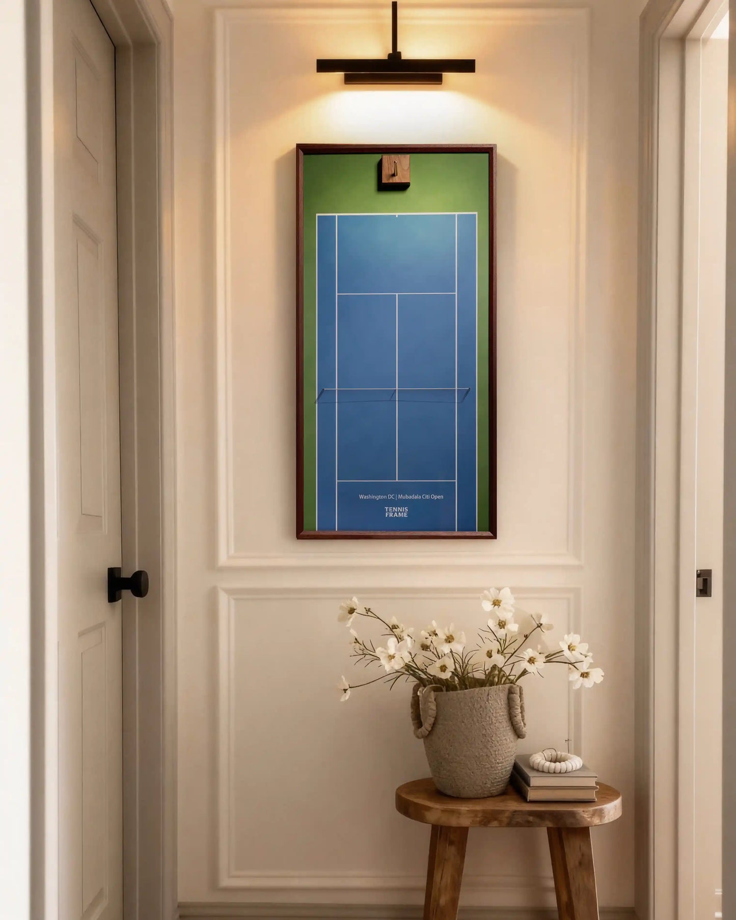 Washington DC Mubadala Citi Open tennis racket display frame with blue hard-court background and walnut frame, styled in a hallway with picture light and floral side table